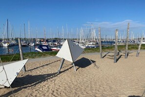 Ein Strand mit sandigem Ufer und einer Reihe von Booten, die im Wasser liegen.