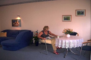 A person seated at a table with a vase of flowers, a lamp, and framed pictures on the wall. - Holiday apartment with 1 bedroom (Lübbenau)