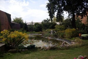 A garden with a pond, a small bridge, and a variety of plants and trees. - Holiday apartment with 1 bedroom (Lübbenau)