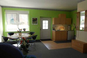 Eine kleine Küche mit Essbereich, einem Kühlschrank und einem Fenster mit Vorhängen.