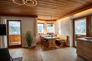 A wooden interior with a dining area, a potted plant, and large windows. - Most stylish sky lodge (Leutasch)