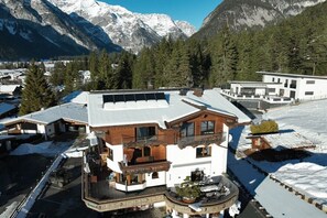 A chalet-style building with a snow-covered roof, surrounded by trees and mountains. - Most stylish sky lodge (Leutasch)