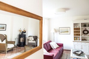 A living room with a fireplace, a sofa, a coffee table, and a bookshelf. - Holiday apartment with 1 bedroom (Zingst)