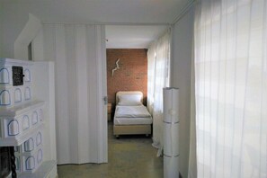 A bedroom with a bed, a brick wall, and a white wardrobe. - Holiday apartment with 3 bedrooms (Sierksdorf)