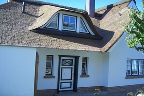 A house with a steeply pitched roof, a white exterior, and a black-framed front door. - Luxury holiday home by the sea (Mönchgut Ortsteil Gager)