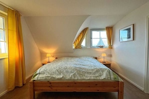 A bedroom with a single bed, two bedside lamps, a window with curtains, and a framed picture on the wall. - Luxury holiday home by the sea (Mönchgut Ortsteil Gager)