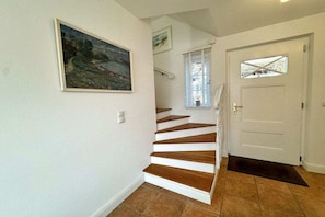 A staircase leading to a door with a doormat, a painting on the wall, and a window with blinds. - Luxury holiday home by the sea (Mönchgut Ortsteil Gager)