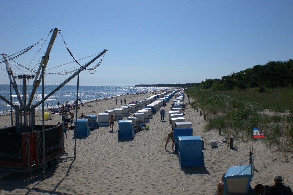 Une plage bordée de rangées de cabanes de plage bleues et surmontée d’une tour de surveillance des sauveteurs.