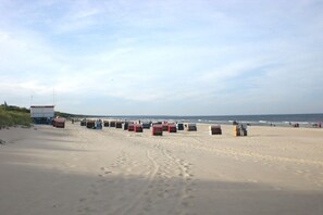A beach with a row of containers and a large white structure on the left. - Holiday home with 4 bedrooms (Zinnowitz)