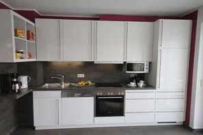 A modern kitchen with white cabinets, a black oven, a microwave, and a sink. - Holiday home with 4 bedrooms (Zinnowitz)