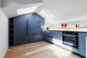 A modern kitchen with a skylight, built-in appliances, and a wooden floor. - Elegant penthouse in the historic center of Treviso—2 bedrooms, 2 bathrooms, and a terrace (Treviso)