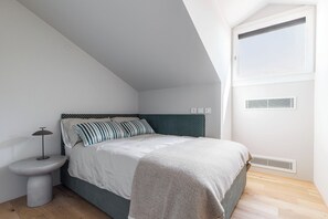 A bedroom with a single bed, a bedside table, a lamp, and a window with a view. - Elegant penthouse in the historic center of Treviso—2 bedrooms, 2 bathrooms, and a terrace (Treviso)