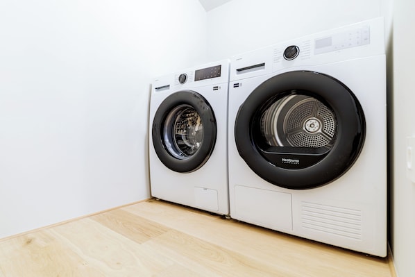 A pair of front-loading washing machines in a laundry room with a wooden floor. - Elegant penthouse in the historic center of Treviso—2 bedrooms, 2 bathrooms, and a terrace (Treviso)