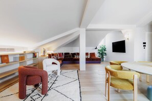 A modern loft-style living space with a high ceiling, a dining area, and a seating area with a large window. - Elegant penthouse in the historic center of Treviso—2 bedrooms, 2 bathrooms, and a terrace (Treviso)