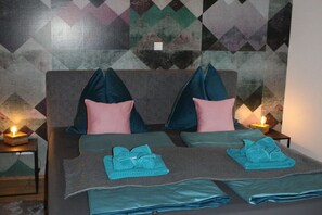 A double bed with two pillows, a blanket, and a folded towel on each side. There are two bedside tables with candles. - ||---------------------Penthouse SkyView-----------------|| (Patergassen - Bad Kleinkirchheim (Österreich))