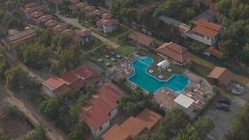 An aerial view of a residential area with multiple houses, a swimming pool, and a small garden area.