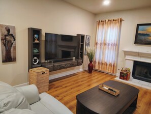 Un salon comprenant un canapé, un téléviseur à écran plat, une cheminée et un vase décoratif.