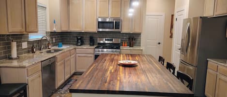 Una cocina moderna con gabinetes de madera, electrodomésticos de acero inoxidable y una isla central.