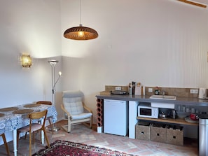 Une cuisine compacte comprenant un coin repas, un four à micro-ondes, un réfrigérateur et un luminaire suspendu.