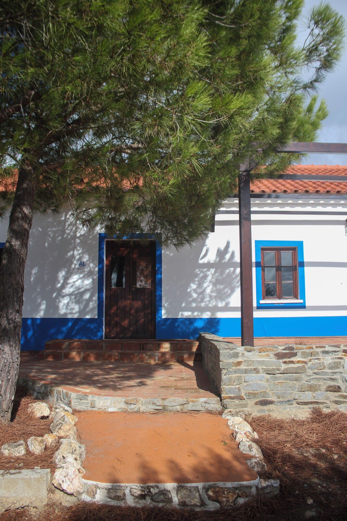 Um edifício tradicional com base de pedra, porta de madeira e janela com moldura azul.