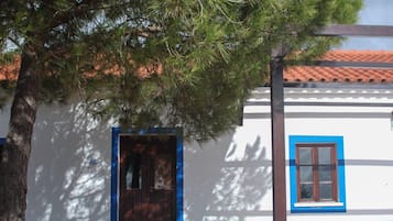 Um edifício tradicional com base de pedra, porta de madeira e janela com moldura azul.