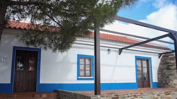 Un bâtiment à la façade blanche, aux ornements bleus et doté d’un mur en pierre.