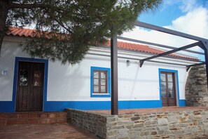 Un bâtiment à la façade blanche, aux ornements bleus et doté d’un mur en pierre.