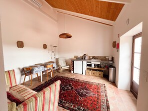 Un espace de vie compact comprenant un coin repas, un canapé, une cuisine et un tapis à motifs.