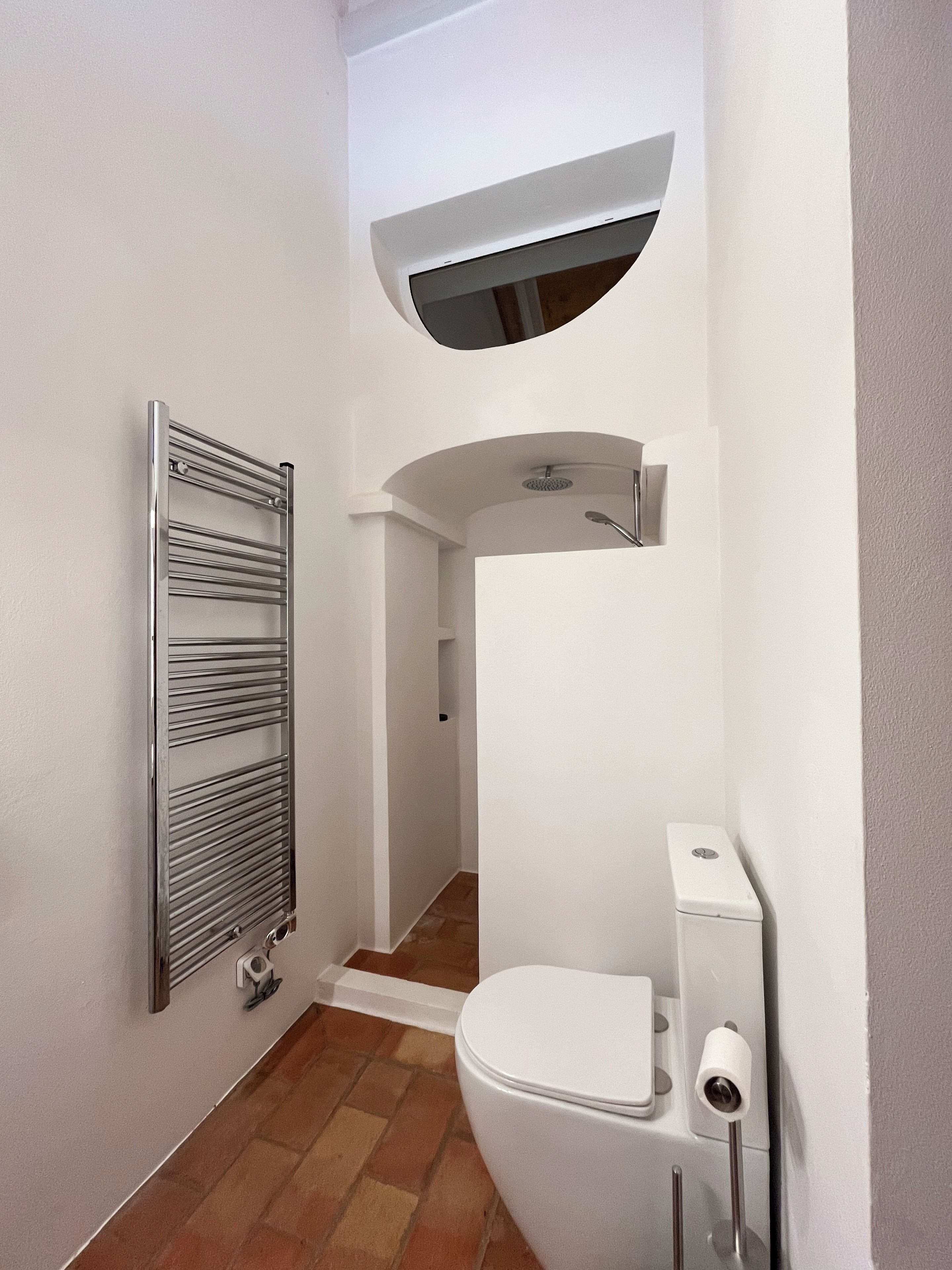 Une petite salle de bain comprenant des toilettes, une douche et un porte-serviettes.