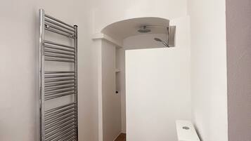 Une petite salle de bain comprenant des toilettes, une douche et un porte-serviettes.