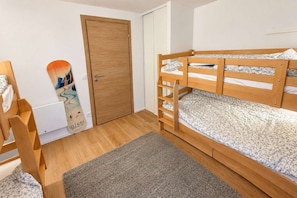 Habitación con literas, una puerta de madera y un cartel en la pared.