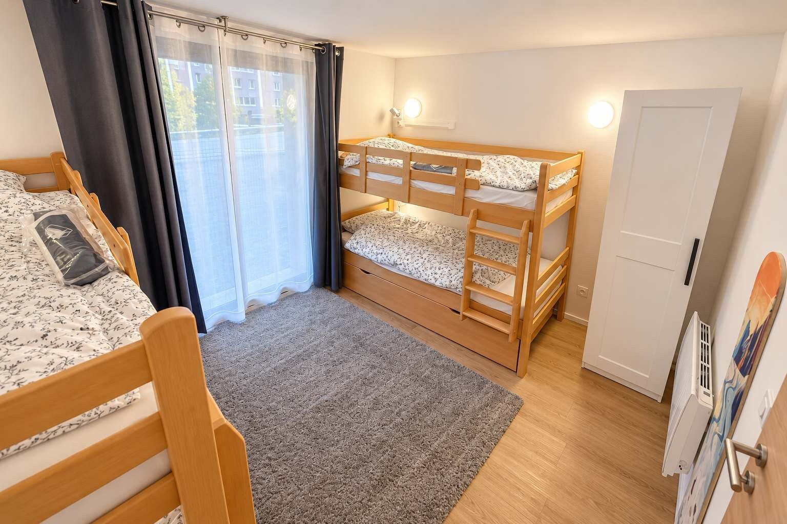 A room with two bunk beds, a window with curtains, a door, and a small rug.