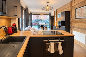 Una cocina moderna con encimera de madera, electrodomésticos negros y vistas al exterior.