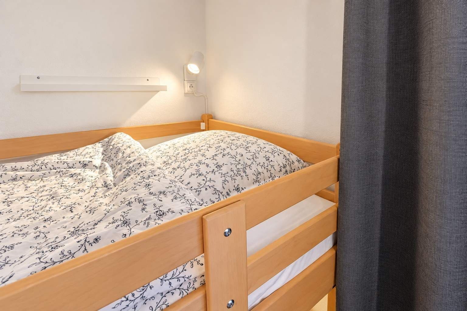 A single bed with a wooden frame and a floral-patterned bedspread.