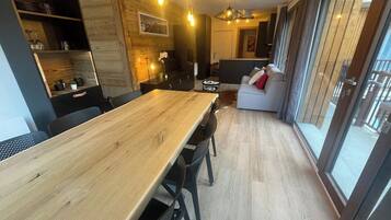 A modern kitchen with a wooden table, black chairs, and pendant lighting.