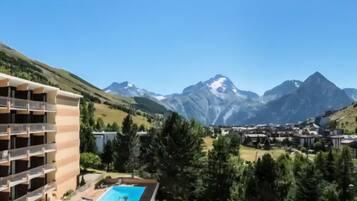 Un hôtel à plusieurs étages, doté d’une piscine et offrant une vue sur les montagnes.