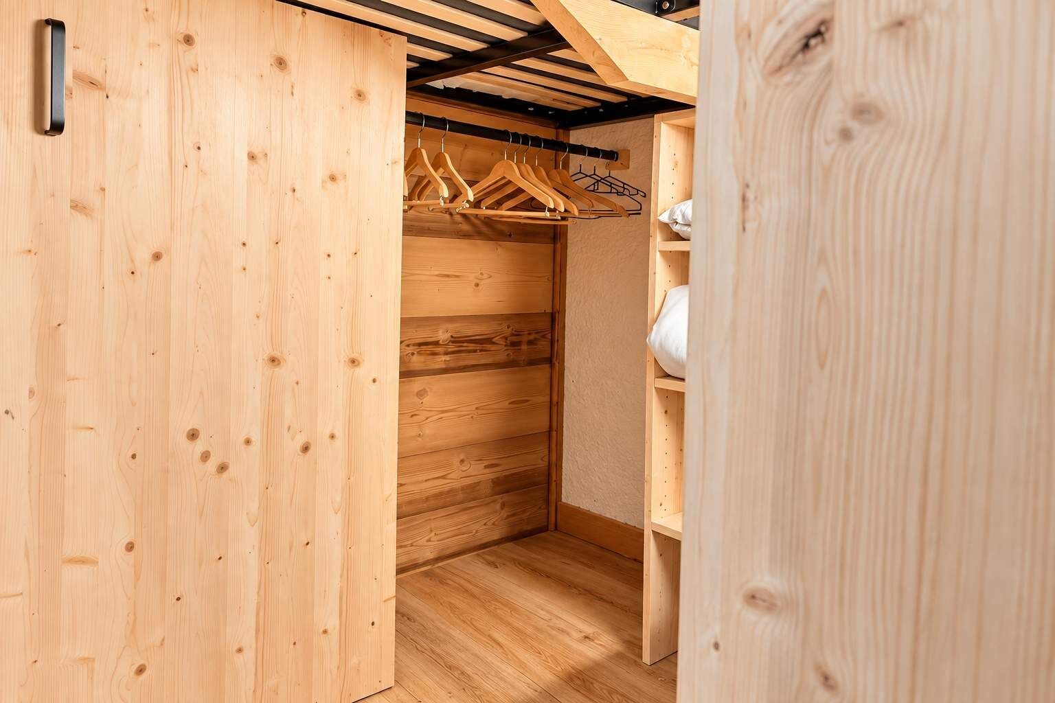 Un placard en bois avec une tringle pour suspendre les vêtements et une étagère.