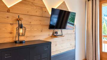 Ein modernes Zimmer mit einer Holzvertäfelung, einem Wandfernseher, einem Schrank und einer Lampe.
