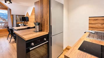 Een compacte keuken met een Bosch koelkast, een inbouwoven en een houten aanrecht.