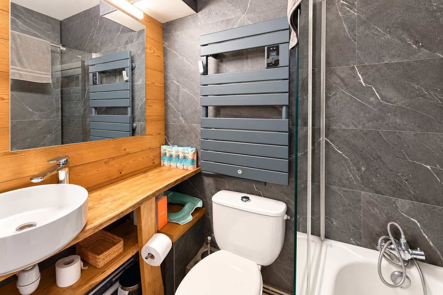 Ein modernes Badezimmer mit einem Holzlagerfläschchen, einem großen Spiegel, einer Toilette und einer Duschkabine.