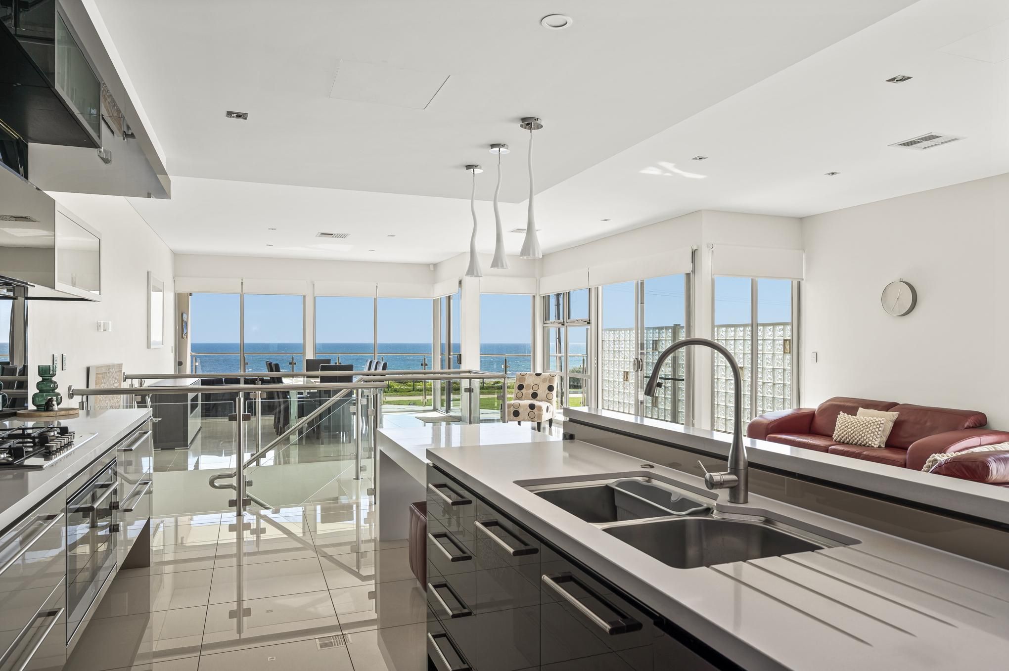 A modern kitchen with a large island, stainless steel appliances, and a view of the ocean.