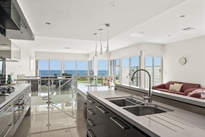 A modern kitchen with a large island, stainless steel appliances, and a view of the ocean. - Ocean 100 ~ Aldinga Beach - Ultimate Beachfront Family Escape (Aldinga Beach)