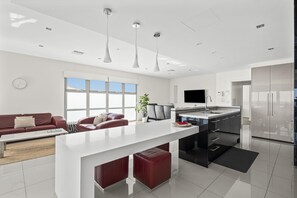 Una cocina moderna con una isla central, un área de comedor con sofá y un ventanal que proporciona luz natural.