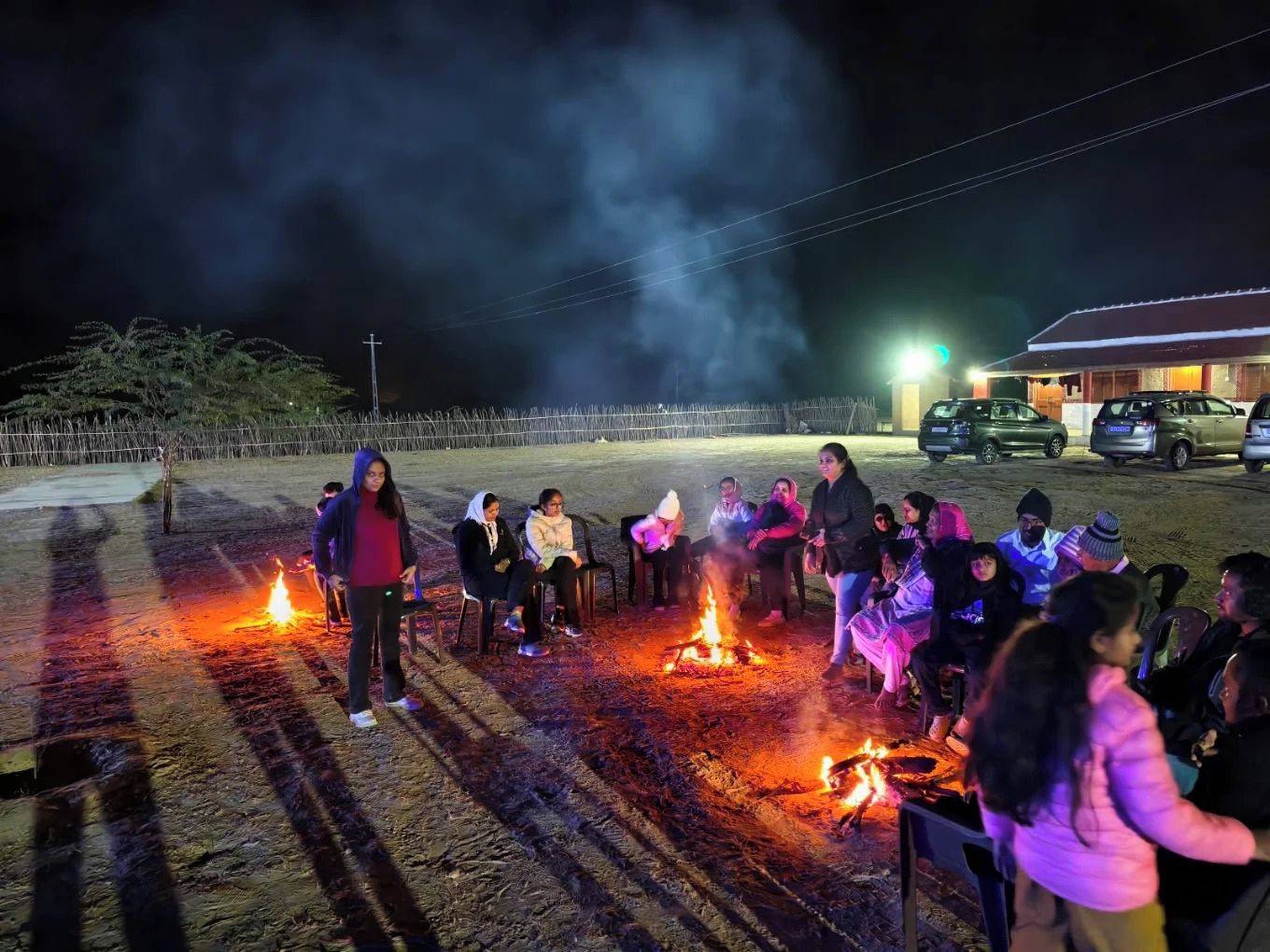 Un grupo de personas reunidas alrededor de una fogata por la noche.