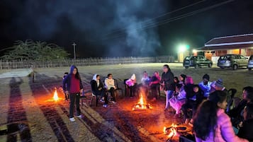 Un grupo de personas reunidas alrededor de una fogata por la noche.