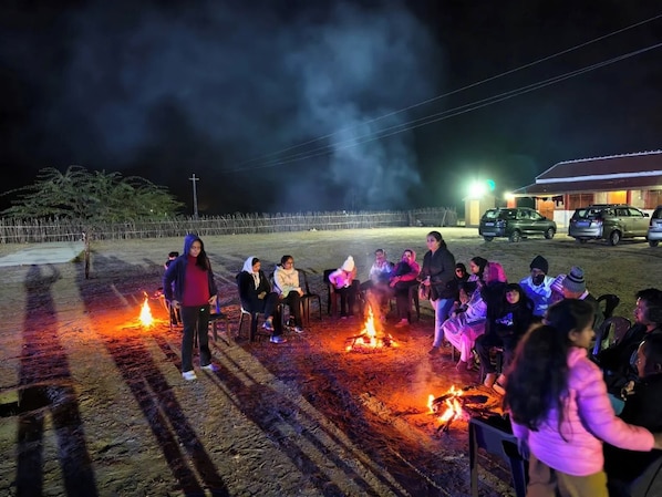 Un grupo de personas reunidas alrededor de una fogata por la noche.