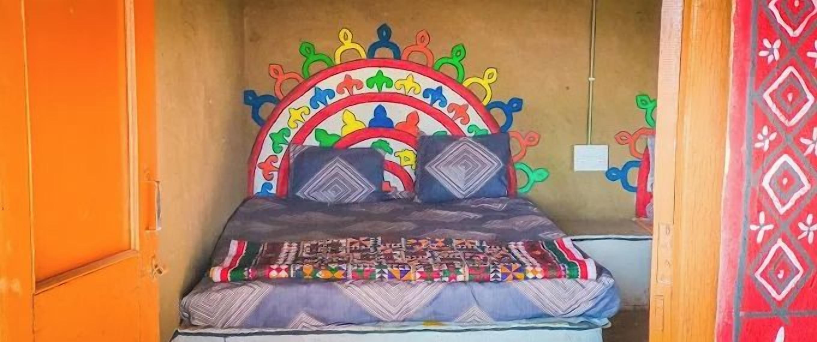 Una cama con un cabecero colorido y una colcha estampada.
