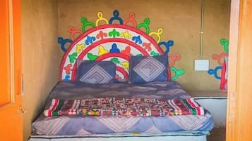 Una cama con un cabecero colorido y una colcha estampada.