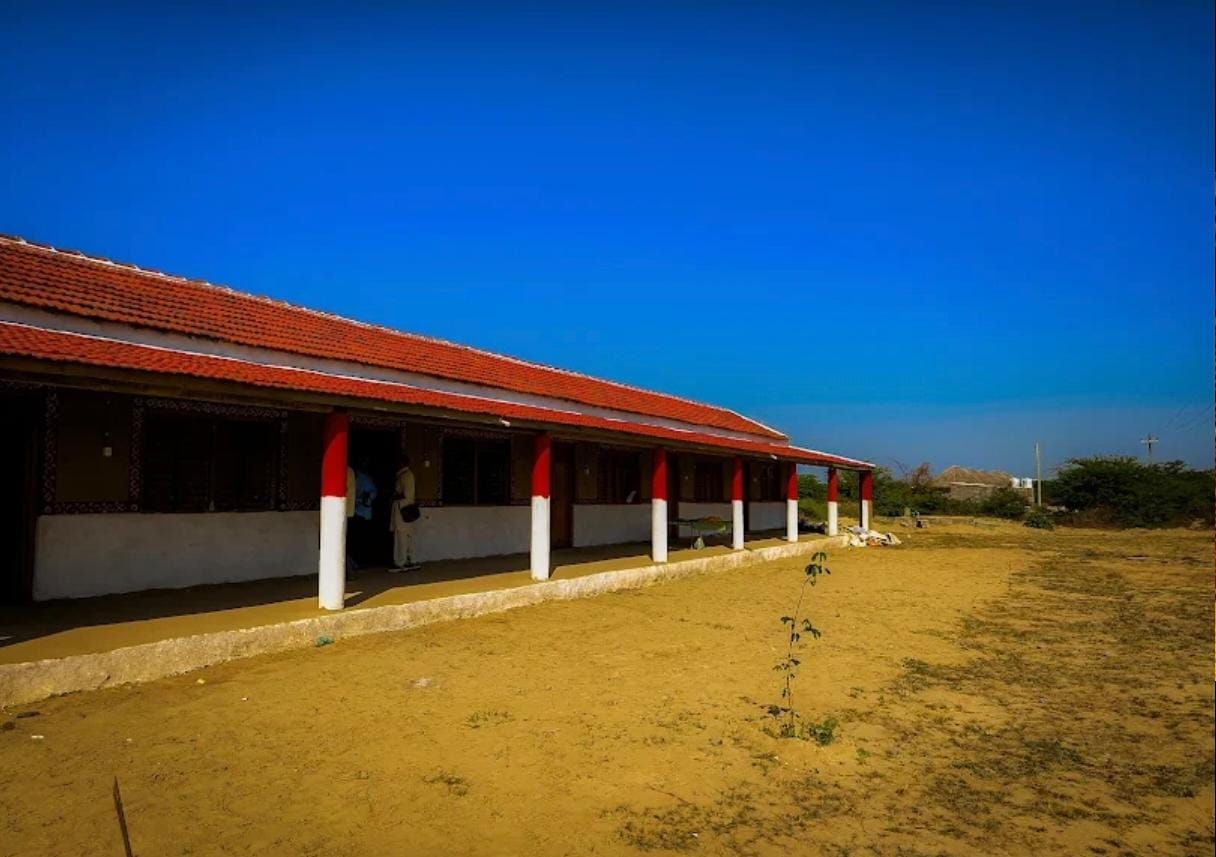 Un edificio con techo rojo y pilares blancos, un área exterior cubierta y cielo despejado.
