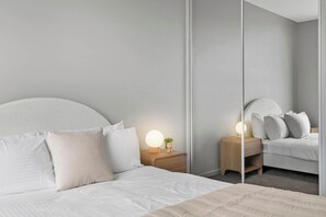 Une chambre moderne avec un grand lit, des tables de chevet, un miroir et une petite table de nuit.